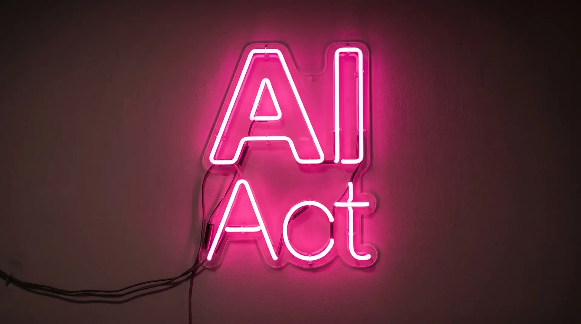 Neon-Schild mit dem Text AI Act in leuchtendem Pink an einer dunklen Wand